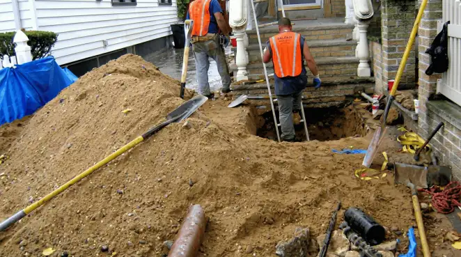 Contractors performing foundation protection and exterior drainage excavation near residential home steps in Irvine, CA